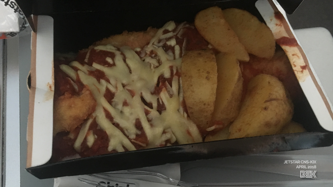 Chicken parmigiana with potato wedges, in a cardboard box with plastic cutlery.
